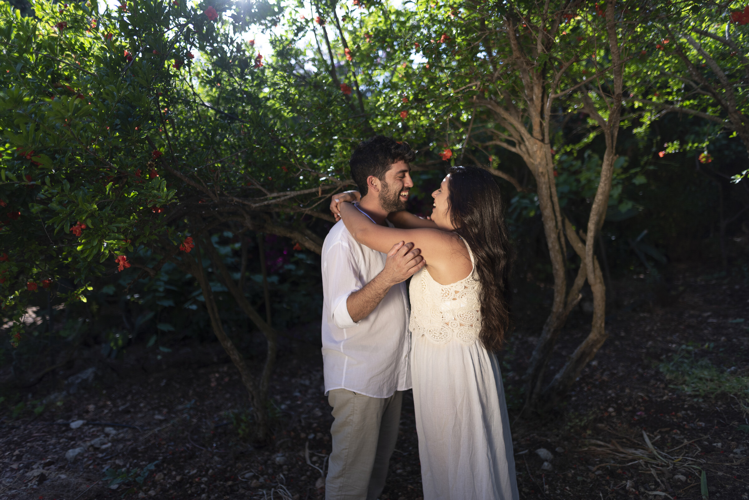 Couple laughing together among flowering pomegranate branches