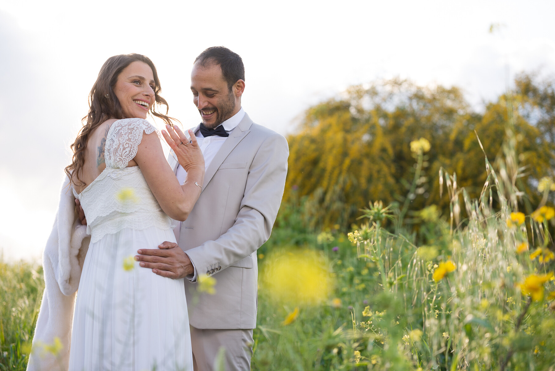 Bride glancing back over her shoulder, laughing in a wildflower field